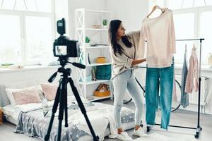 mulher jovem e bonita em roupas casuais fazendo vídeo de mídia social enquanto passa o tempo em casa foto