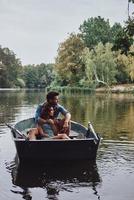 pouca viagem. lindo casal jovem abraçando enquanto desfruta de um encontro romântico no lago foto