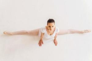 bailarina fazendo espacates. vista superior da jovem bailarina em tutu branco fazendo divisões foto