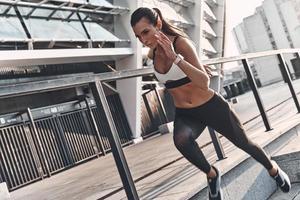 sua melhor velocidade. mulher jovem e moderna em roupas esportivas correndo enquanto se exercita ao ar livre foto