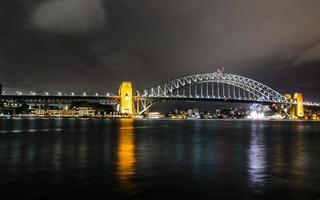 fotografia noturna da ponte do porto de sydney em noite nublada. foto