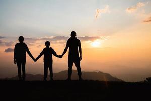 família feliz. silhueta mãe pai e filho na natureza da montanha no pôr do sol. foto