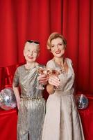 duas mulheres maduras e sênior comemorando o ano novo segurando nas mãos copos de vinho espumante branco. natal, família, amigos, comemorando, conceito de ano novo foto