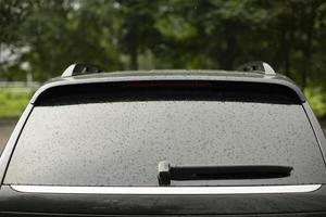 vidro molhado do carro nas costas. cai de carro. veículos pretos no estacionamento. foto