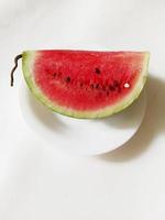 melancia fatiada em um prato em um fundo branco foto