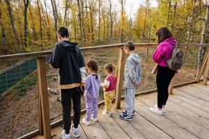 família com quatro filhos olhando animais selvagens da ponte de madeira. foto