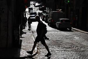 silhueta de um homem atravessando uma estrada pavimentada em um dia ensolarado foto