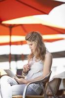 jovem sentada em um café de rua com tablet digital