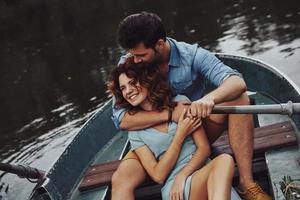 feitos para amar uns aos outros. lindo casal jovem abraçando e sorrindo enquanto desfruta de um encontro romântico no lago foto