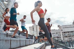 grupo de jovens em roupas esportivas correndo enquanto se exercita nas escadas ao ar livre foto