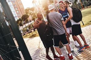 ótimo dia com amigos. grupo de jovens em roupas esportivas sorrindo em pé ao ar livre foto