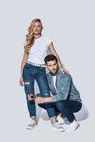 estilo jeans. comprimento total do belo casal jovem se unindo em pé contra um fundo cinza foto