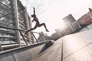 apenas voando. comprimento total da jovem moderna em roupas esportivas pulando durante o exercício ao ar livre foto