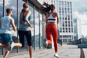 vista traseira de pessoas em roupas esportivas correndo durante o exercício na calçada ao ar livre foto