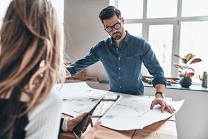 dia de trabalho duro. dois jovens empresários modernos em roupas casuais inteligentes usando planta enquanto trabalhavam no espaço de trabalho criativo foto