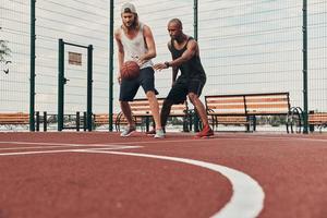 dois jovens em roupas esportivas jogando basquete e sorrindo enquanto passam o tempo ao ar livre foto