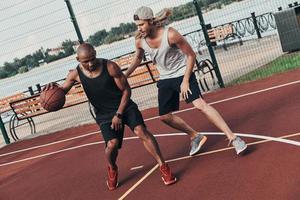 competidores de basquete. dois jovens em roupas esportivas jogando basquete enquanto passam tempo ao ar livre foto