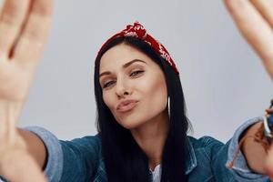 mulher jovem e atraente em bandana olhando para a câmera e fazendo moldura de mão foto