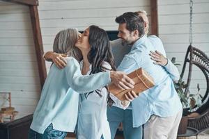 pais idosos alegres conhecendo jovem casal dentro de casa foto