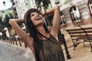 Felicidade pura. mulher jovem e atraente, mantendo as mãos atrás da cabeça e sorrindo em pé ao ar livre foto