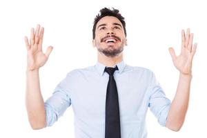 empresário de sucesso. jovem feliz de camisa e gravata, mantendo os braços levantados e sorrindo em pé contra um fundo branco foto