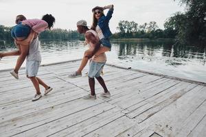 sempre felizes juntos. comprimento total de belos casais jovens passando tempo despreocupado em pé no cais foto