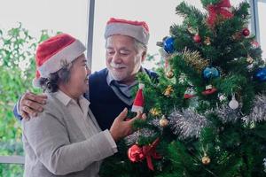 casal sênior decorando a árvore de natal foto