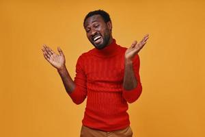 bonito jovem africano em roupas casuais, gesticulando e sorrindo foto