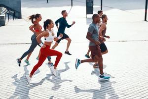 vista superior de corpo inteiro de pessoas em roupas esportivas correndo enquanto se exercita na calçada ao ar livre foto