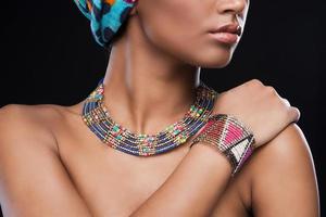 joias elegantes. foto recortada de linda mulher africana usando um lenço na cabeça e joias em pé contra um fundo preto