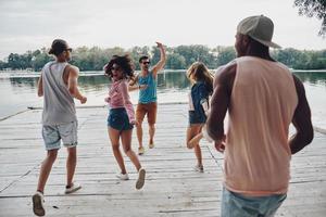 se divertindo. grupo de jovens em roupas casuais sorrindo e gesticulando enquanto desfruta da festa na praia foto