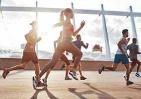 comprimento total de pessoas em roupas esportivas correndo enquanto se exercita na calçada ao ar livre foto