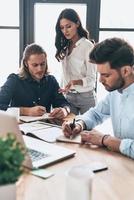 colaboração é a chave para melhores resultados. jovens colegas modernos em roupas casuais inteligentes trabalhando juntos enquanto passam o tempo no escritório foto