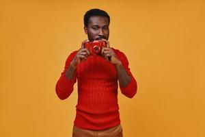 jovem africano bonito em roupas casuais fotografando pela câmera foto