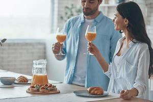 lindo casal jovem tomando café da manhã juntos enquanto passa o tempo na cozinha doméstica