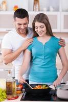 cozinhar juntos é divertido. casal jovem feliz cozinhando juntos na cozinha foto