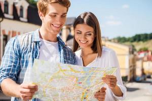 casal examinando o mapa. feliz casal jovem turista examinando o mapa juntos em pé ao ar livre foto