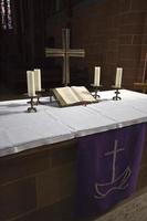 altar com bíblia, cruz e quatro velas