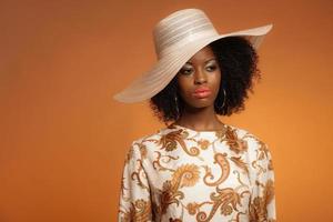 anos 70 retrô moda mulher afro com vestido estampado e chapéu. foto