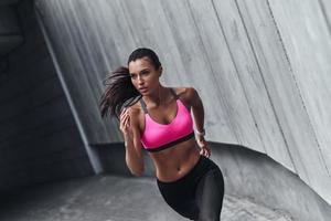 melhor cardio de todos os tempos. mulher jovem e moderna em roupas esportivas correndo enquanto se exercita ao ar livre foto