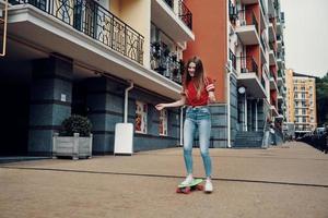 melhor passatempo de todos os tempos. comprimento total de mulher jovem e atraente sorrindo enquanto anda de skate ao ar livre foto