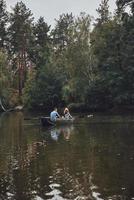 pequena aventura. lindo casal jovem desfrutando de um encontro romântico e sorrindo enquanto remava um barco foto