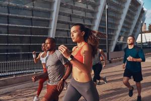 grupo de jovens em roupas esportivas correndo juntos ao ar livre foto