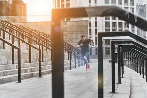 velocidade e potência. comprimento total de jovem em roupas esportivas correndo enquanto se exercita fora foto