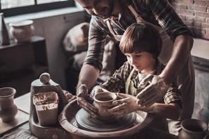 aprendendo nova habilidade de oleiro. vista superior do jovem alegre e garotinho fazendo pote de cerâmica na aula de cerâmica