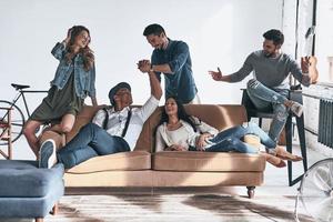 amigos despreocupados. grupo de jovens bonitos em roupas casuais descansando e sorrindo enquanto passam o tempo em casa foto