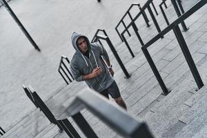 nunca desista. vista superior do jovem em roupas esportivas exercitando em pé nas escadas ao ar livre foto