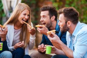 amantes de pizza. grupo de jovens brincalhões comendo pizza enquanto se divertem juntos foto