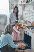 linda avó tirando biscoitos do forno e sorrindo enquanto passa o tempo com a família foto