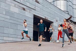 comprimento total de jovens em roupas esportivas correndo enquanto se exercitam na calçada ao ar livre foto